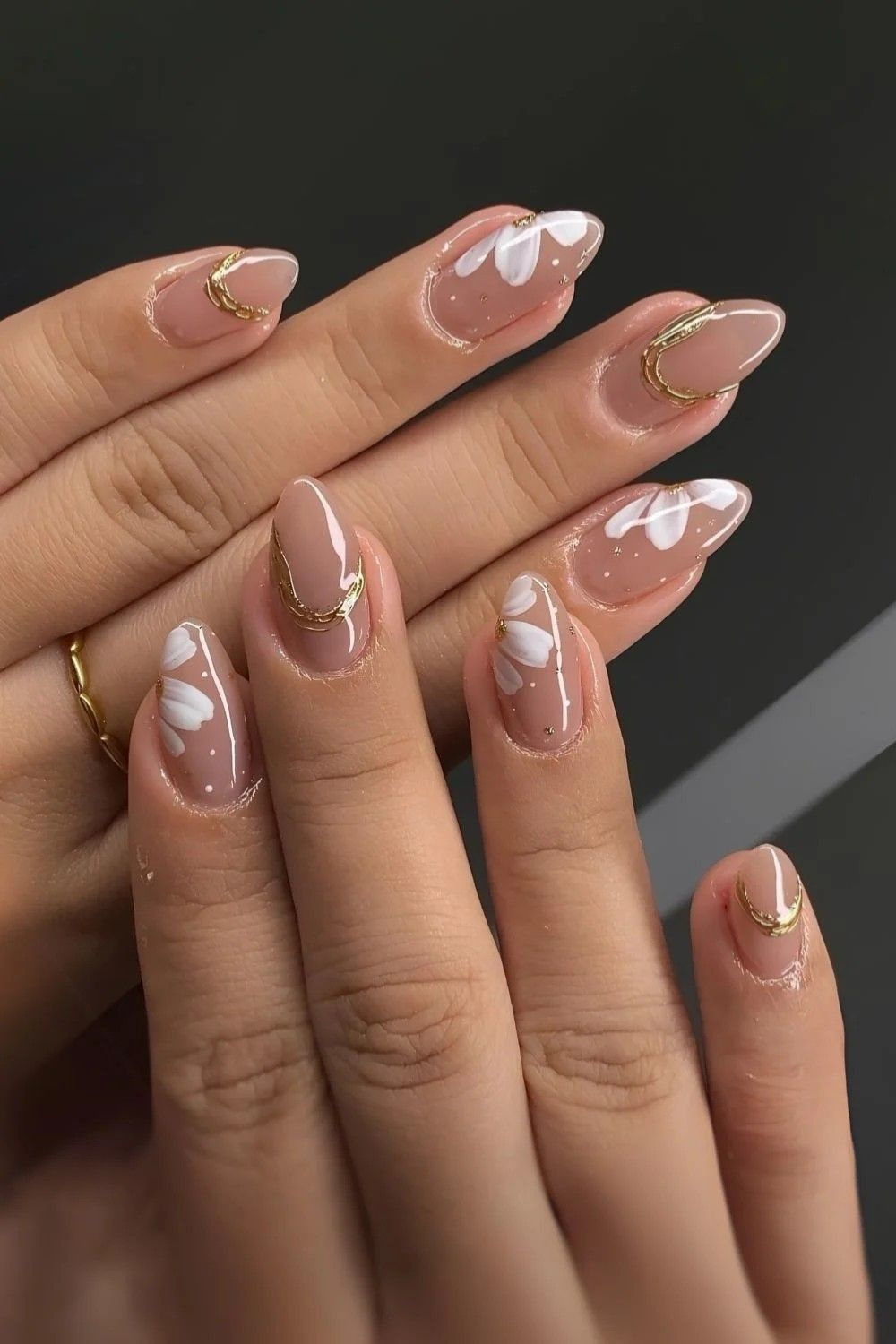 Nude nails with hand-painted white petals and gold accents